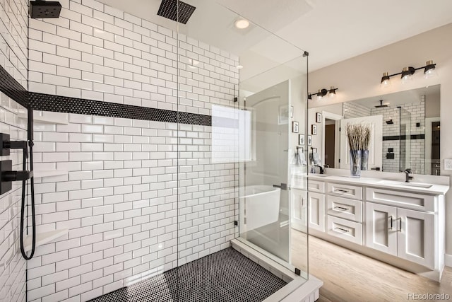 bathroom with vanity, a shower with door, and tile walls