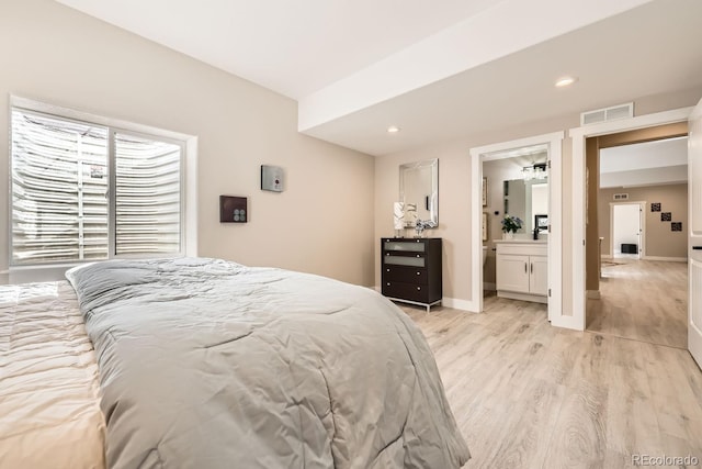 bedroom with light wood-type flooring and ensuite bath