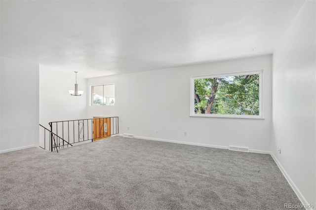 unfurnished room featuring a chandelier and carpet floors