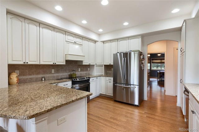 15910 Rhodes Pl, Elbert, CO 80106 - kitchen featuring stainless steel appliances, custom range hood, a peninsula, arched walkways, and light wood-style flooring