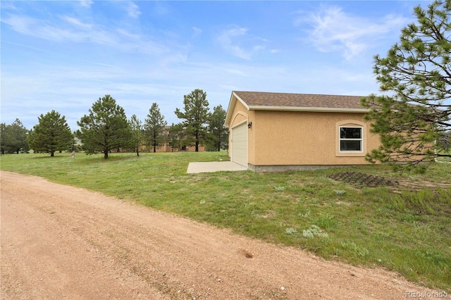 15910 Rhodes Pl, Elbert, CO 80106 - view of side of home with stucco siding, a lawn, and an attached garage