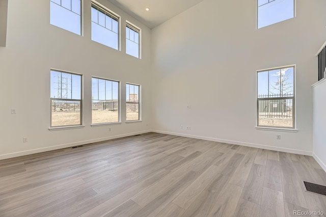 2968 S Poppy St, Morrison, CO 80465 - unfurnished living room with a high ceiling, light wood finished floors, baseboards, and visible vents