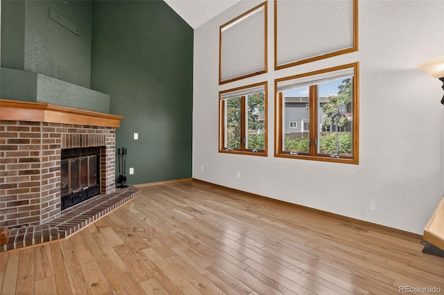 10181 Detroit Ct, Thornton, CO 80229 - unfurnished living room with a high ceiling, a brick fireplace, and hardwood / wood-style floors