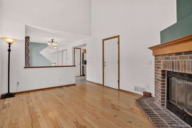 10181 Detroit Ct, Thornton, CO 80229 - unfurnished living room with a brick fireplace, a high ceiling, hardwood / wood-style floors, and a chandelier