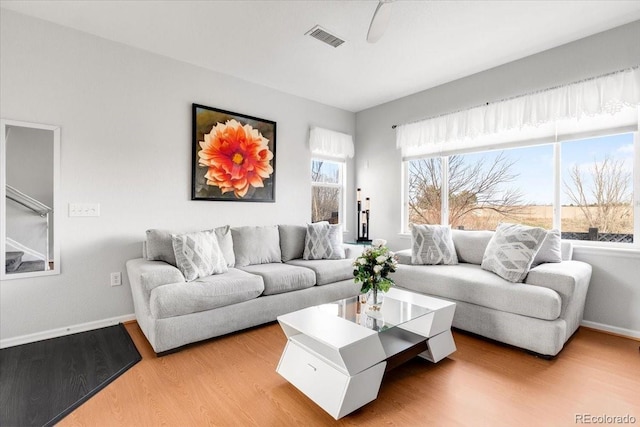 living room featuring light wood-style floors, visible vents, and baseboards