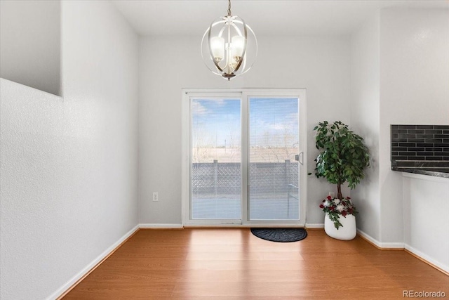 entryway with baseboards, a chandelier, and wood finished floors