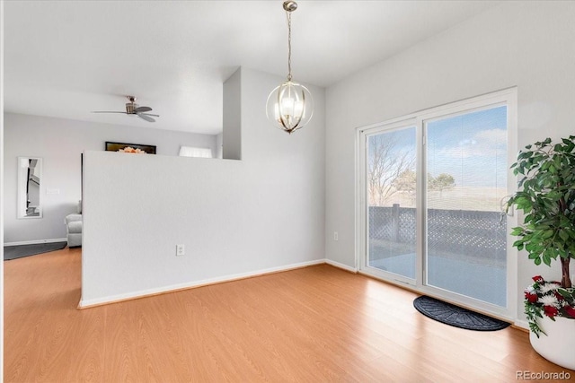 interior space with a ceiling fan, baseboards, and wood finished floors