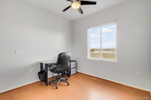 home office featuring a ceiling fan, wood finished floors, visible vents, and baseboards