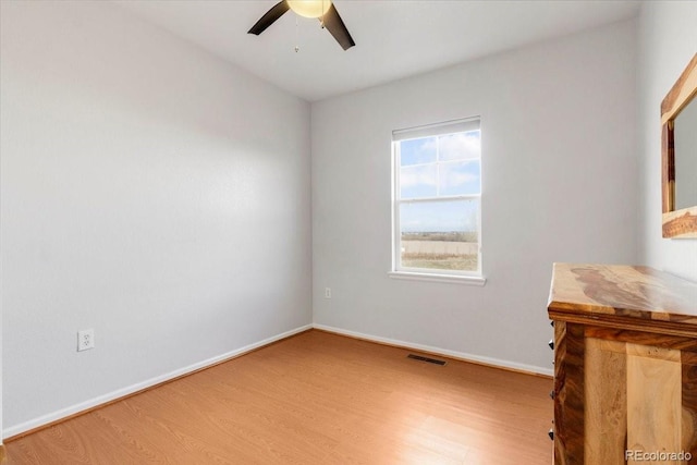 empty room with baseboards, visible vents, ceiling fan, and wood finished floors