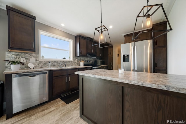 539 W 9th St, Akron, CO 80720 - kitchen with appliances with stainless steel finishes, dark brown cabinets, backsplash, light countertops, and hanging light fixtures