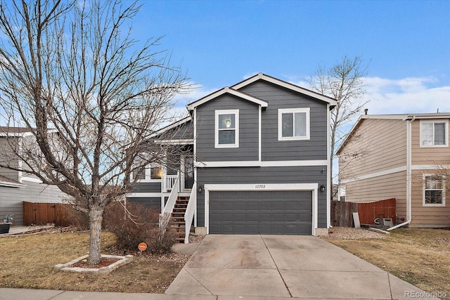 view of front facade featuring driveway, a garage, stairs, and fence