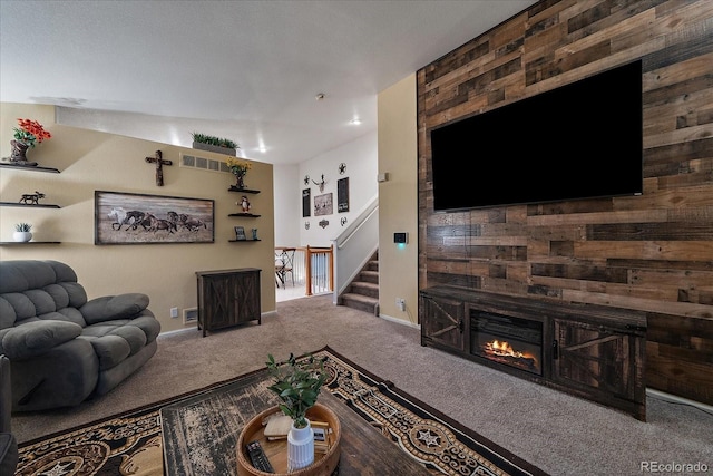 carpeted living area with baseboards, visible vents, stairway, and a glass covered fireplace