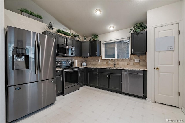 kitchen with tasteful backsplash, lofted ceiling, appliances with stainless steel finishes, light floors, and a sink