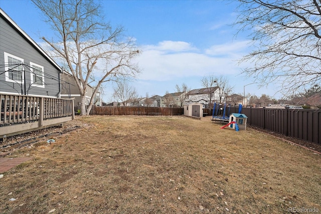 view of yard featuring a storage shed, a deck, an outdoor structure, and a fenced backyard