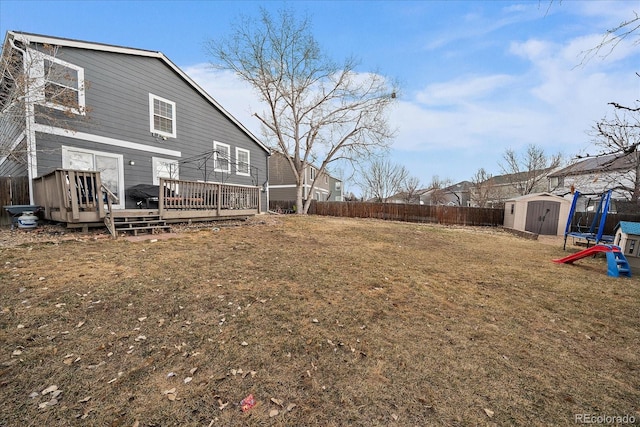 view of yard with an outbuilding, a fenced backyard, a deck, and a storage unit