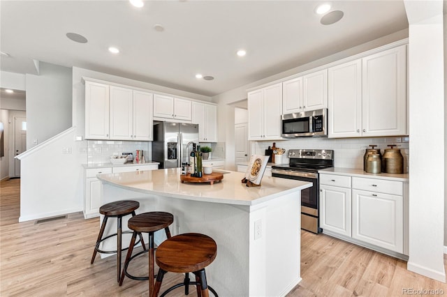 3331 N Buchanan Way, Aurora, CO 80019 - kitchen featuring white cabinetry, appliances with stainless steel finishes, light wood-style flooring, and backsplash