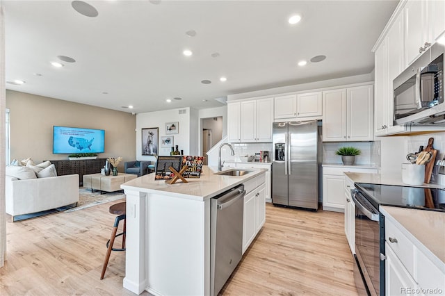 3331 N Buchanan Way, Aurora, CO 80019 - kitchen with a sink, light wood-type flooring, white cabinetry, backsplash, and appliances with stainless steel finishes