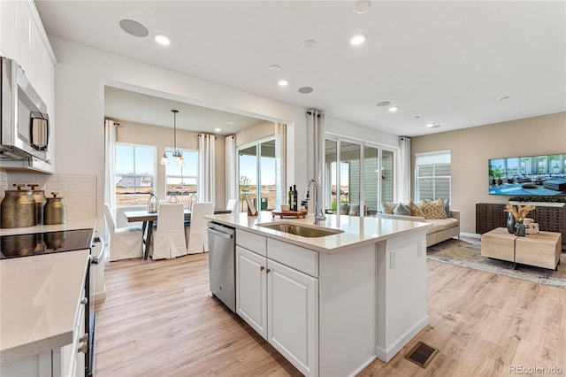 3331 N Buchanan Way, Aurora, CO 80019 - kitchen featuring a sink, white cabinetry, open floor plan, and appliances with stainless steel finishes