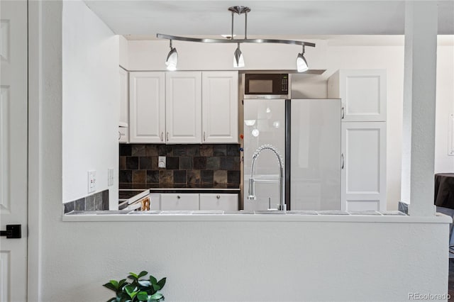 kitchen featuring kitchen peninsula, white cabinetry, pendant lighting, and tasteful backsplash