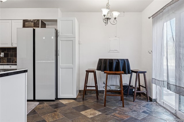 kitchen with white cabinetry, tasteful backsplash, a notable chandelier, pendant lighting, and refrigerator