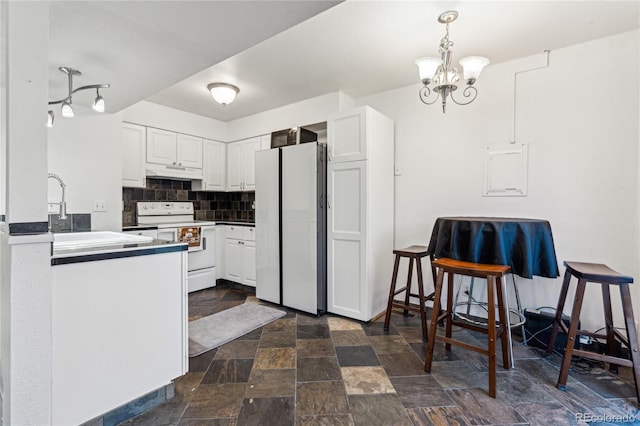 kitchen featuring white appliances, pendant lighting, white cabinetry, backsplash, and a notable chandelier