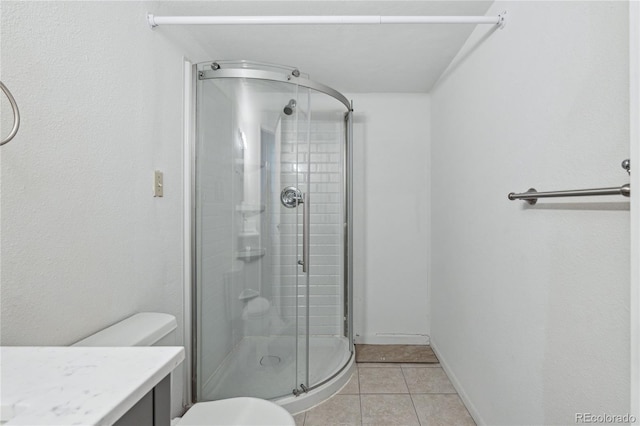 bathroom featuring toilet, vanity, a shower with door, and tile patterned floors