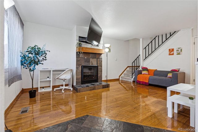 living room featuring wood-type flooring and a tiled fireplace