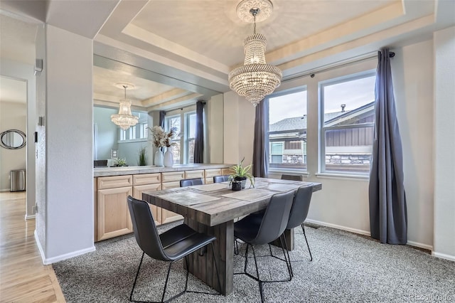 dining room with light colored carpet, a tray ceiling, and a chandelier