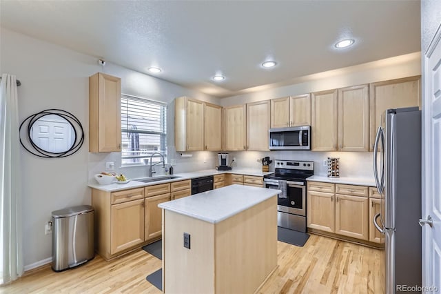 kitchen featuring appliances with stainless steel finishes, a kitchen island, light brown cabinetry, and sink