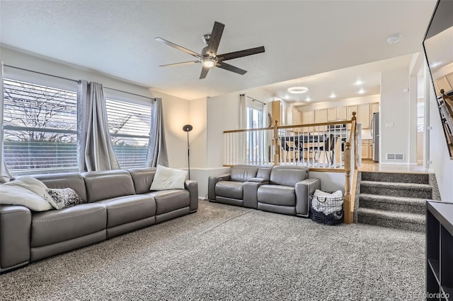 carpeted living room featuring ceiling fan and a textured ceiling