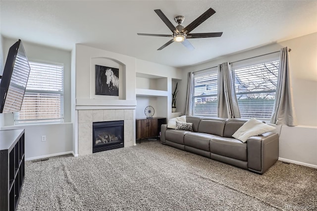 living room with ceiling fan, a fireplace, carpet, and a textured ceiling