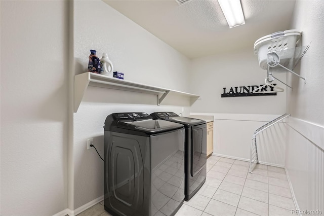 clothes washing area featuring washer and dryer, light tile patterned floors, and a textured ceiling