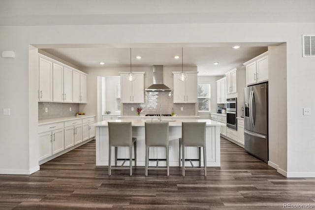 11151 W 53rd Dr, Wheat Ridge, CO 80033 - kitchen with wall chimney exhaust hood, stainless steel appliances, dark wood finished floors, light countertops, and a kitchen island with sink