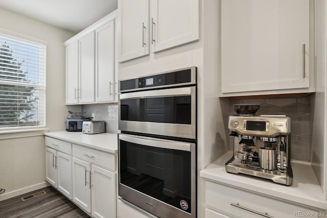 11151 W 53rd Dr, Wheat Ridge, CO 80033 - kitchen featuring double oven, decorative backsplash, white cabinets, light countertops, and dark wood-style floors