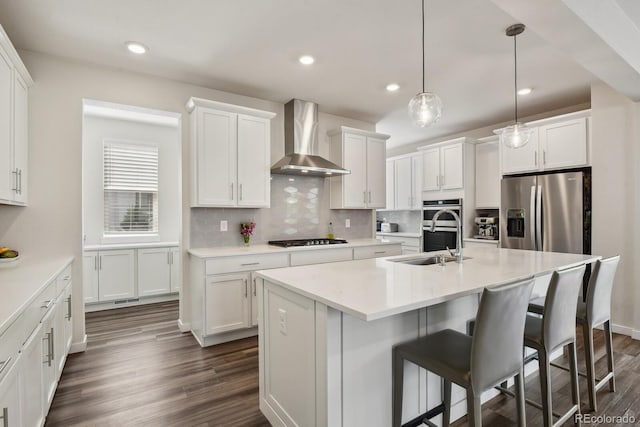 11151 W 53rd Dr, Wheat Ridge, CO 80033 - kitchen featuring wall chimney exhaust hood, stainless steel appliances, a center island with sink, white cabinetry, and tasteful backsplash