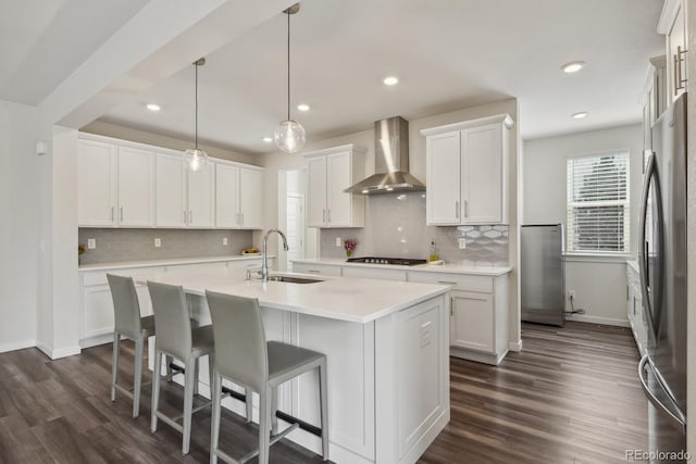 11151 W 53rd Dr, Wheat Ridge, CO 80033 - kitchen with wall chimney range hood, a center island with sink, freestanding refrigerator, white cabinetry, and recessed lighting
