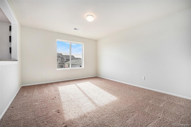 spare room with carpet, visible vents, and baseboards