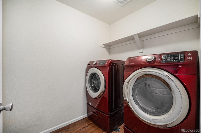 laundry area featuring visible vents, washing machine and dryer, wood finished floors, laundry area, and baseboards