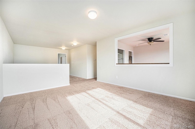 carpeted spare room with ceiling fan and baseboards