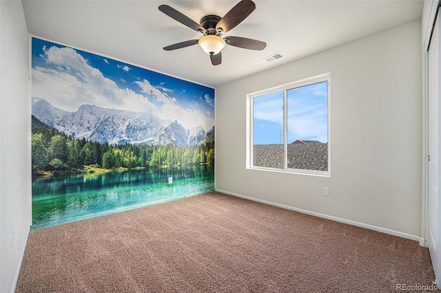 carpeted empty room featuring baseboards, visible vents, and a ceiling fan