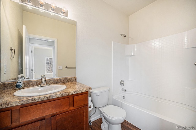 bathroom featuring toilet, wood finished floors, visible vents, vanity, and tub / shower combination