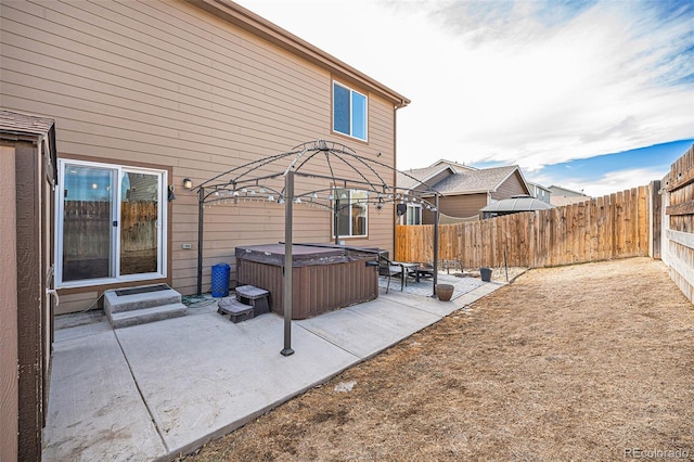 view of patio featuring a hot tub, a fenced backyard, and entry steps