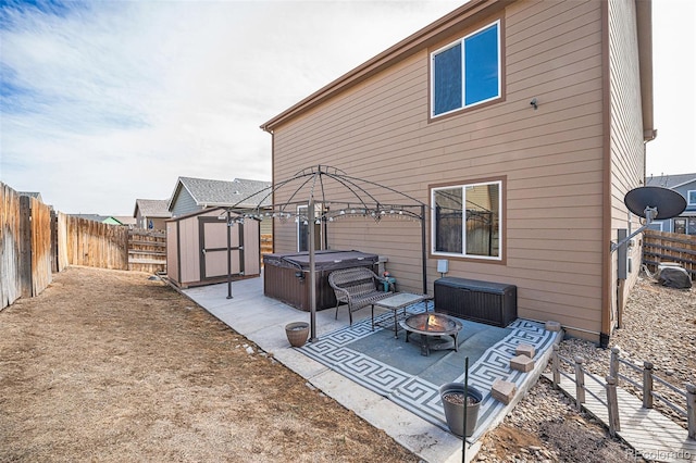 rear view of house featuring a hot tub, a fire pit, a fenced backyard, a patio area, and a shed