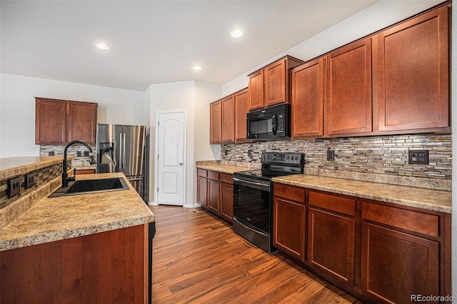 kitchen with electric stove, dark wood-type flooring, a sink, black microwave, and stainless steel fridge