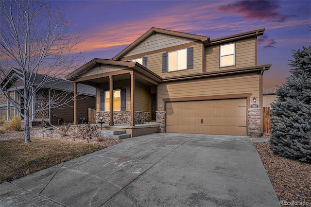 view of front of home featuring a garage, concrete driveway, a porch, and stone siding