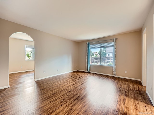 3708 S Lisbon Way, Aurora, CO 80013 - empty room featuring healthy amount of natural light, arched walkways, and wood finished floors