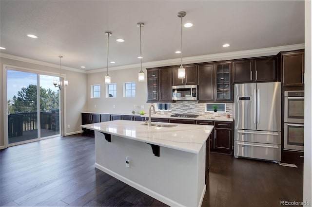 kitchen featuring appliances with stainless steel finishes, a breakfast bar, pendant lighting, sink, and a center island with sink