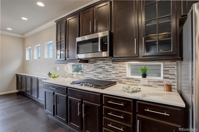 kitchen featuring crown molding, dark brown cabinets, appliances with stainless steel finishes, dark hardwood / wood-style flooring, and decorative backsplash