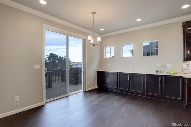 unfurnished dining area featuring dark hardwood / wood-style flooring, sink, ornamental molding, and a chandelier