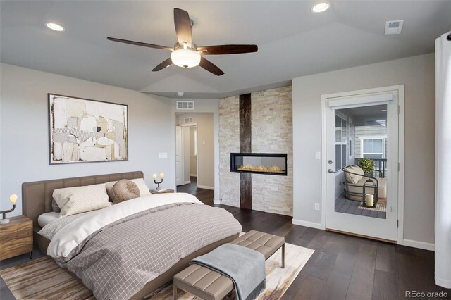 bedroom with a fireplace, dark hardwood / wood-style floors, and ceiling fan